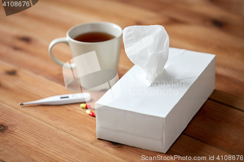 Image of cup of tea, paper wipes and thermometer with pills