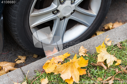 Image of close up of car wheel and autumn leaves