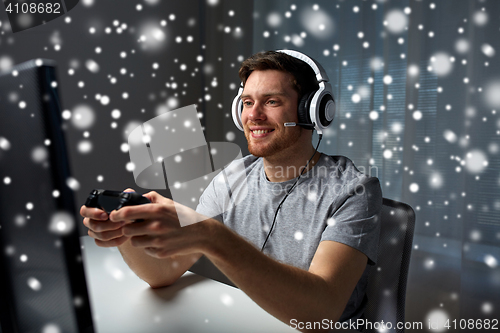 Image of man in headset playing computer video game at home