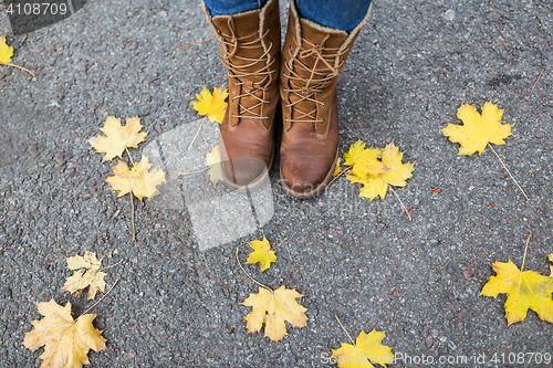 Image of female feet in boots and autumn leaves