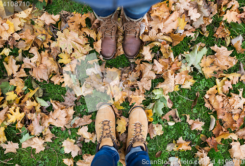 Image of couple of feet in boots and autumn leaves