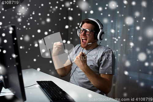 Image of man in headset playing computer video game at home