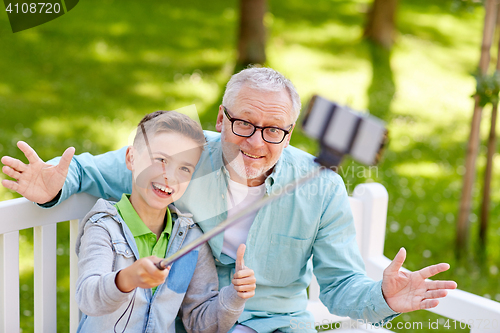 Image of old man and boy taking selfie by smartphone