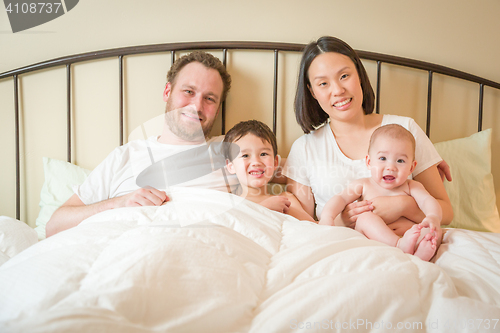 Image of Mixed Race Chinese and Caucasian Baby Boys Laying In Bed with Th