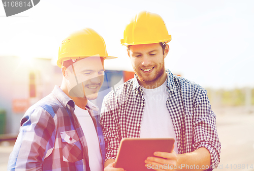 Image of smiling builders in hardhats with tablet pc