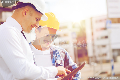 Image of smiling builders in hardhats with tablet pc