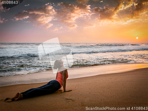 Image of Woman practices yoga asana Urdhva Mukha Svanasana at the beach