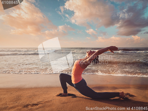 Image of Sporty fit woman practices yoga Anjaneyasana at beach on sunset