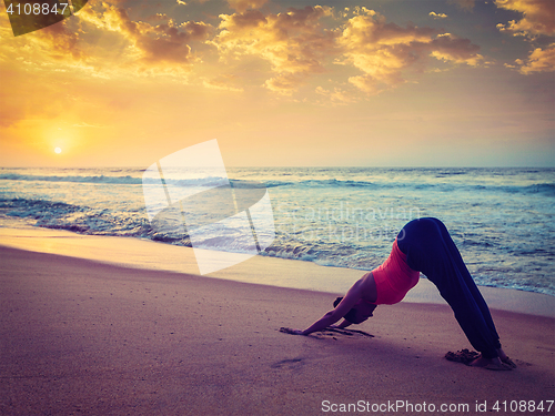 Image of Young sporty fit woman doing yoga at beach on sunset