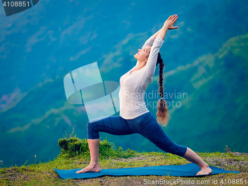 Image of Woman doing yoga asana Virabhadrasana 1 - Warrior pose outdoors