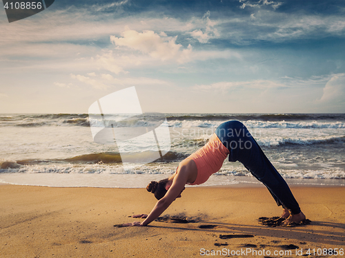 Image of Young sporty fit woman doing yoga oudoors at tropical beach