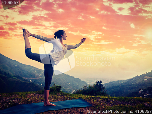 Image of Woman doing yoga asana Natarajasana outdoors at waterfall