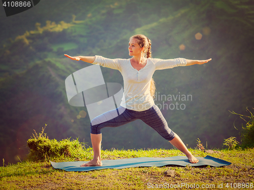 Image of Woman doing yoga asana Virabhadrasana 2 - Warrior pose outdoors