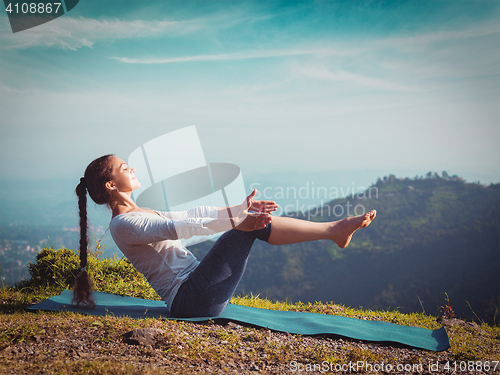 Image of Woman doing Ashtanga Vinyasa Yoga asana Navasana - boat pose