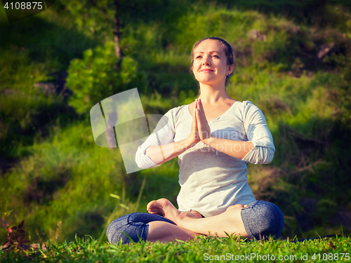 Image of Young sporty fit woman doing yoga Lotus pose oudoors 