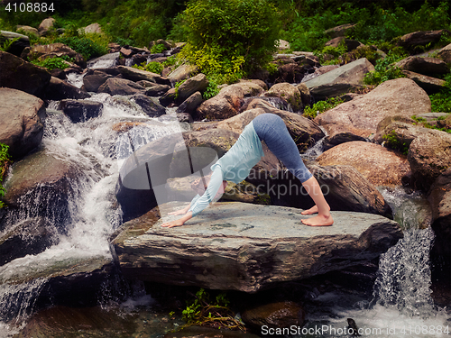 Image of Young sporty fit woman doing yoga oudoors at tropical waterfall