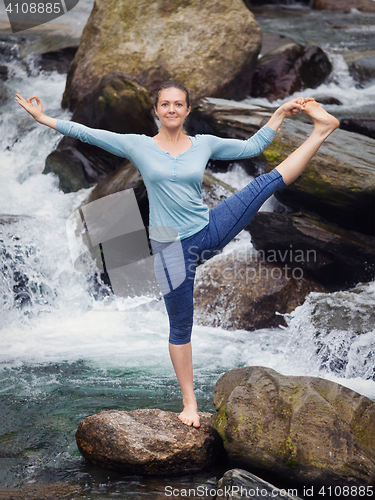 Image of Woman doing Ashtanga Vinyasa Yoga asana outdoors at waterfall