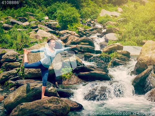 Image of Woman doing yoga asana Natarajasana outdoors at waterfall