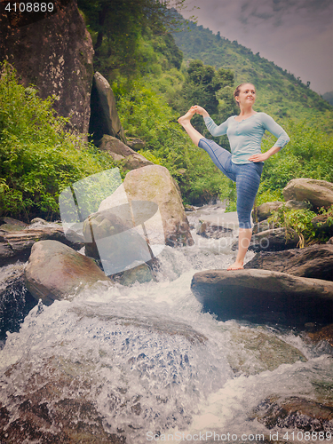 Image of Woman doing Ashtanga Vinyasa Yoga asana outdoors at waterfall