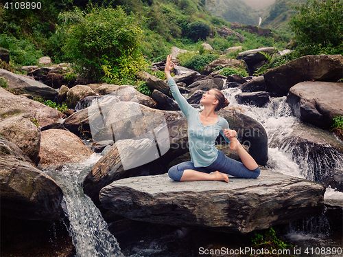 Image of Sorty fit woman doing yoga asana outdoors at tropical waterfall