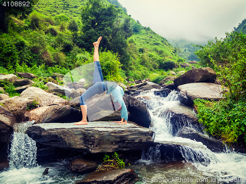 Image of Woman doing yoga asana at waterfall