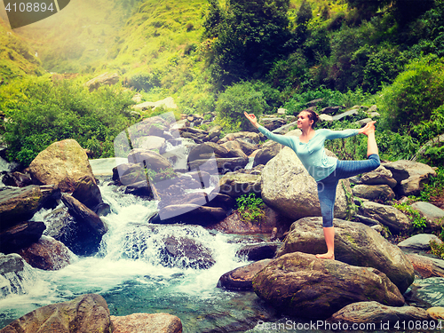 Image of Woman doing yoga asana Natarajasana outdoors at waterfall