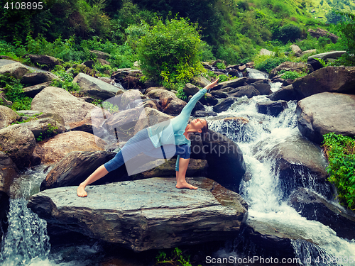 Image of Woman practices yoga asana Utthita Parsvakonasana outdoors