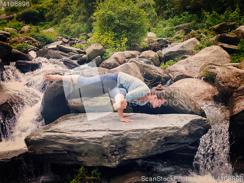 Image of Young sporty fit woman doing yoga oudoors at tropical waterfall