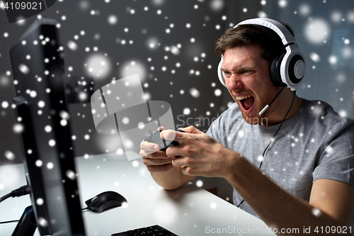 Image of man in headset playing computer video game at home