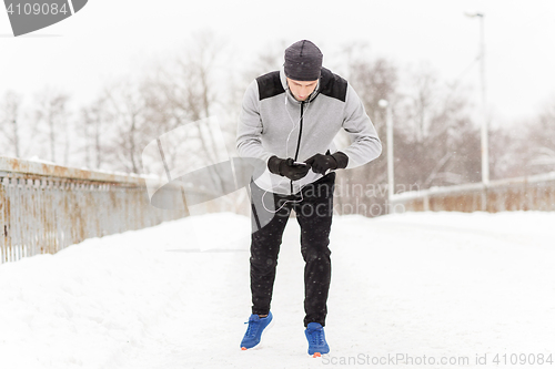 Image of man with earphones and cellphone running in winter