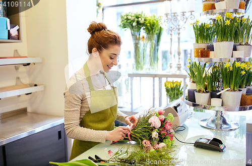 Image of smiling florist woman making bunch at flower shop