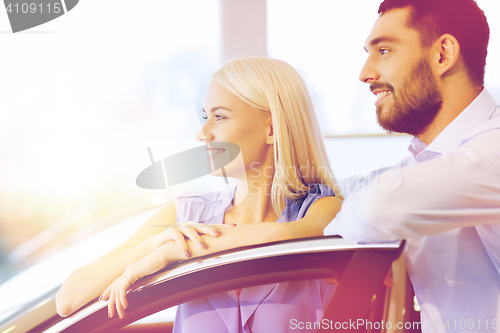 Image of happy couple buying car in auto show or salon