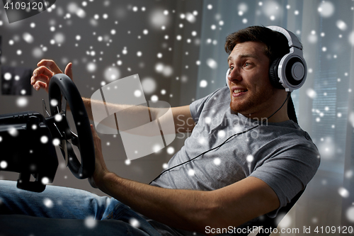 Image of man playing car racing video game at home