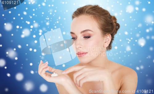 Image of woman with moisturizing cream on hand over snow