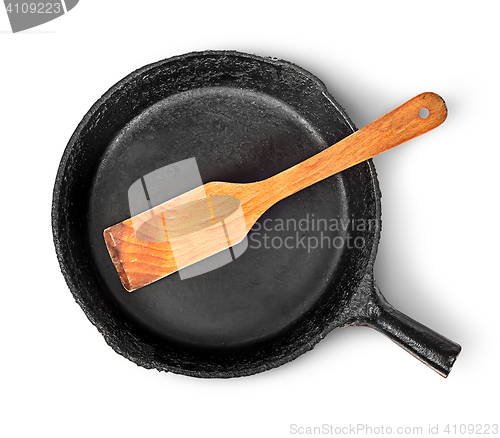 Image of Old cast iron pan with wooden spatula top view