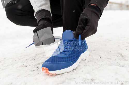 Image of close up of man tying shoe lace in winter outdoors