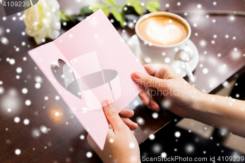 Image of close up of woman reading greeting card and coffee
