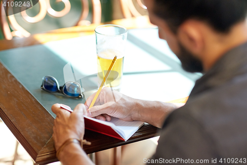 Image of close up of man with beer and notebook at pub