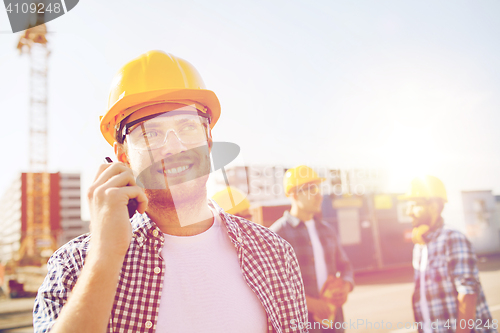 Image of group of smiling builders in hardhats with radio