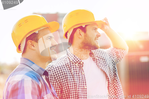 Image of group of smiling builders in hardhats outdoors