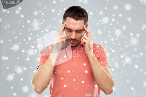 Image of man suffering from head ache or thinking over snow