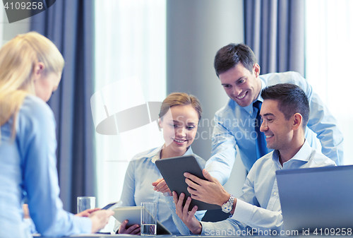 Image of smiling business people with tablet pc in office
