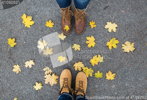 Image of couple of feet in boots and autumn leaves