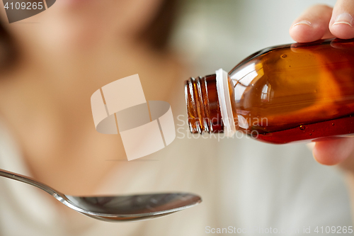 Image of woman pouring medication from bottle to spoon