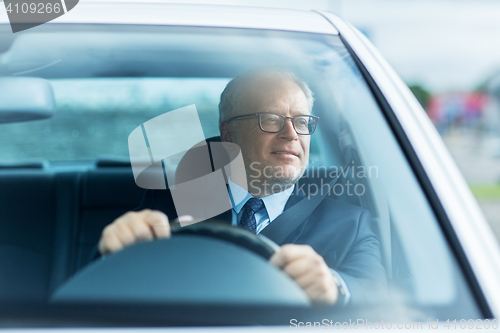 Image of happy senior businessman driving car