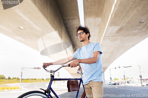 Image of hipster man with fixed gear bike under bridge