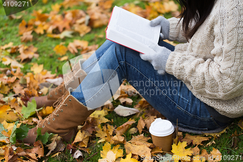 Image of woman with book drinking coffee in autumn park