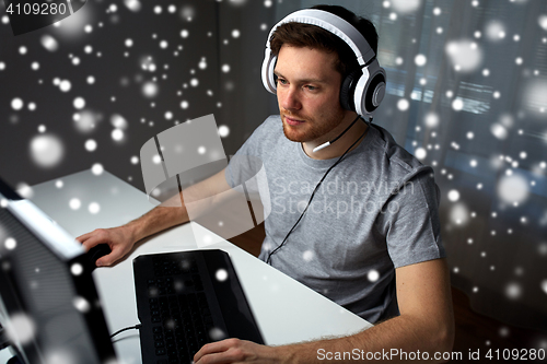 Image of man in headset playing computer video game at home