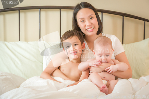 Image of Mixed Race Chinese and Caucasian Baby Boys Laying In Bed with Th