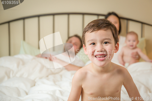 Image of Mixed Race Chinese and Caucasian Boy Laying In Bed with His Fami